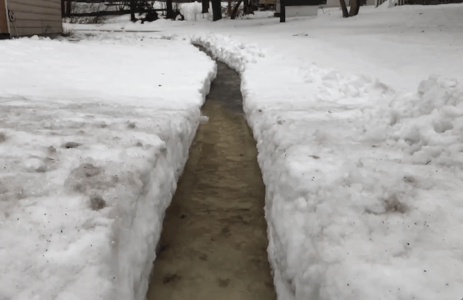 Picture of a river a person shoveled through their yard to divert flood waters from their house.