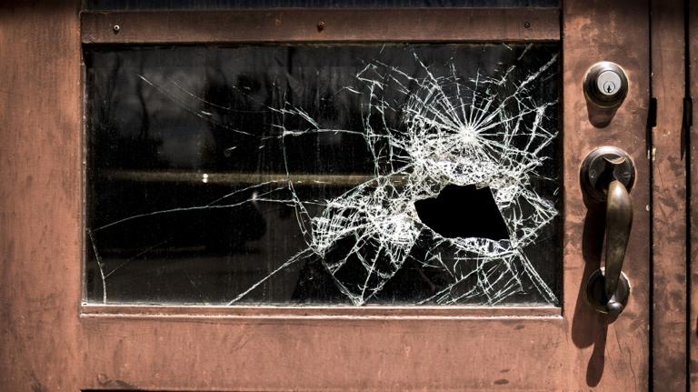 Property damage from vandalism showing broken glass and spray paint requiring professional cleanup
