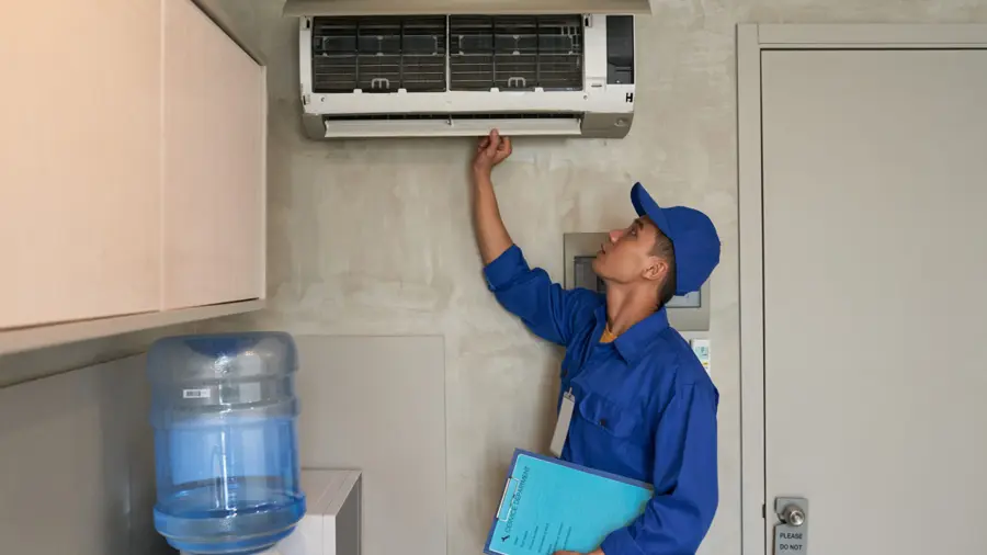 A technician servicing a wall-mounted air conditioning unit