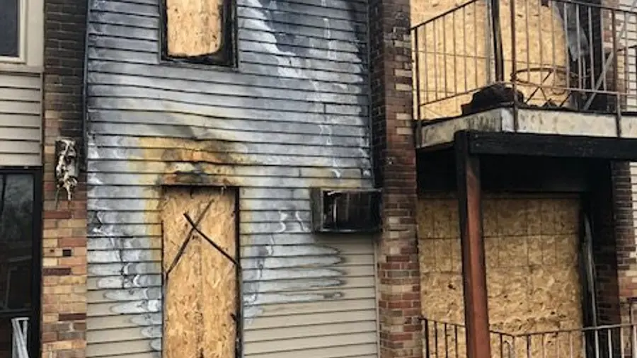 A commercial building with boarded windows after fire damage