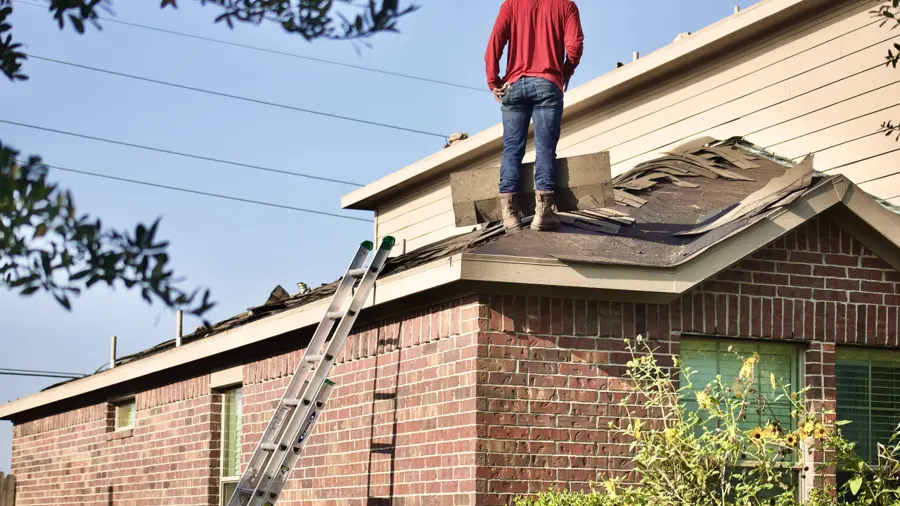 Contractor removing damaged roofing materials during residential roof repair and restoration project